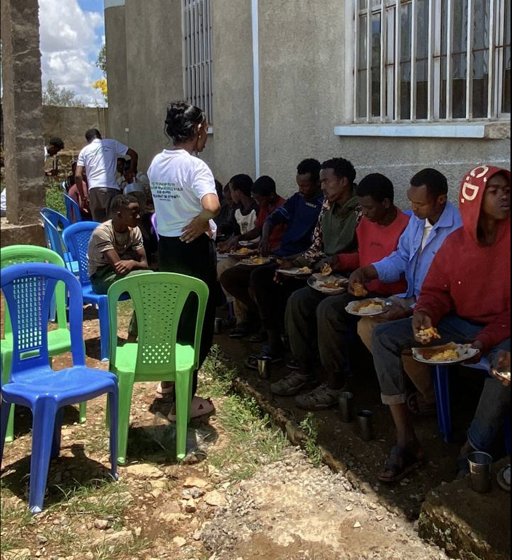 Volunteers serving plates of food to people seated outside