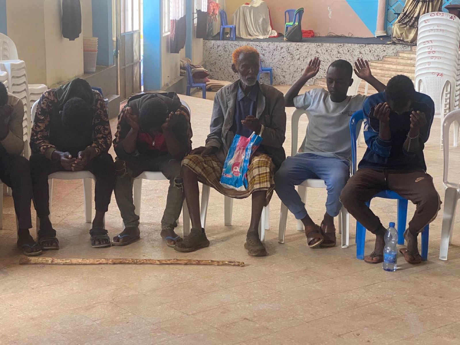 Men praying together with heads bowed and hands raised